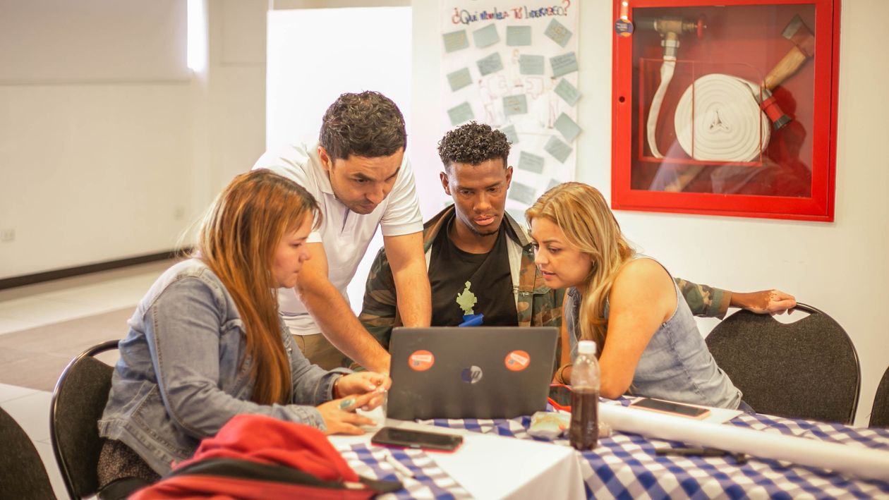 A diverse group collaborating around a laptop during a training session