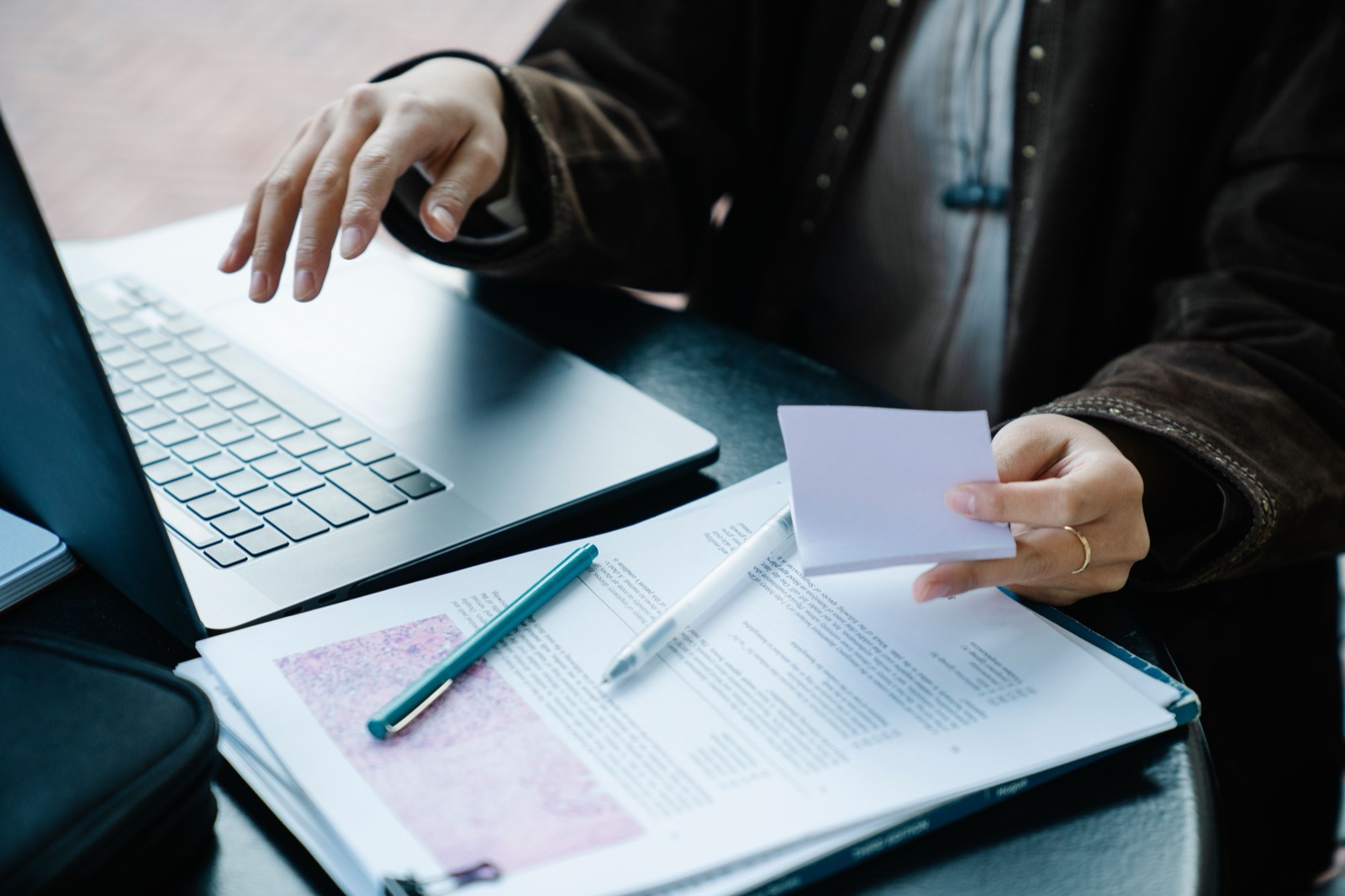 An editor reviewing printed documents beside a laptop
