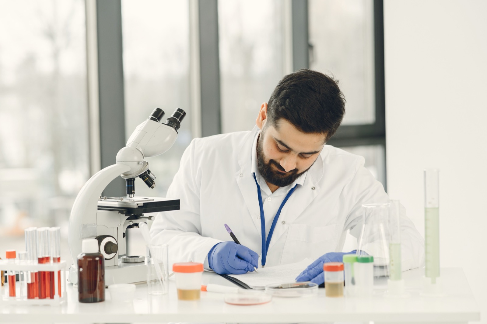 A clinical researcher recording observations beside a microscope