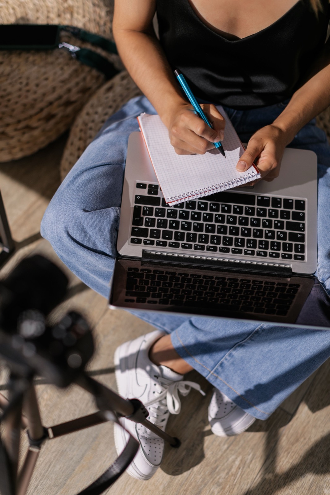 A learner writing in a notebook while using a laptop
